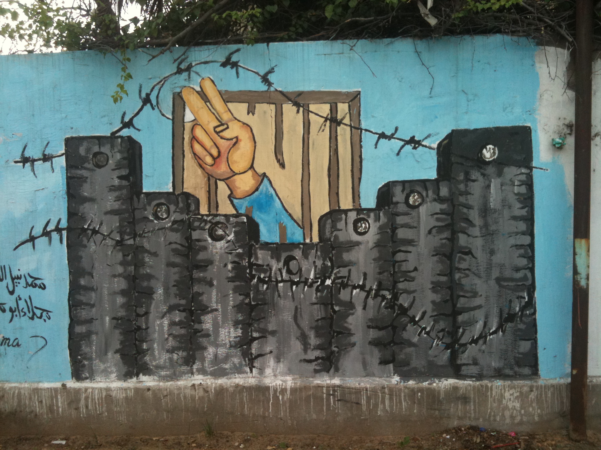 graffitti on a wall showing a handing emerging from a prison cell covered with barbed wire